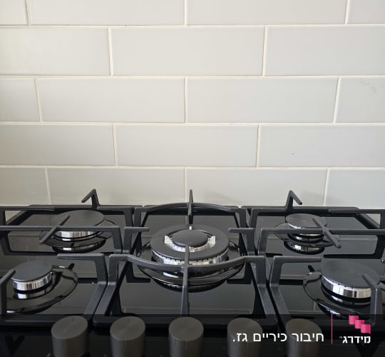 כיריים גז עם כפתורים על רקע קיר לבן